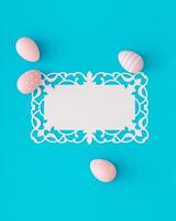 Pink colored eggs on light blue background with paper card note. Minimal Easter concept. Creative festive spring holiday layout. Easter aesthetic with unique copy space. Flat lay, top of view. photo