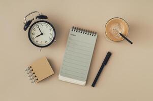 Coffee, To do list notepad, black pen and retro alarm clock. Planner for organization and goal priorities. Writing down tasks and schedule reminders on office desk. Planning concept. Flat lay style. photo