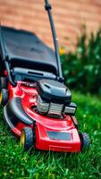 powerful red lawn mower sits on a fresh green lawn ready for work. photo