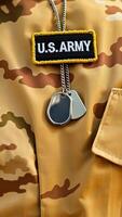 close-up of u.s. army patch and dog tags on camouflage uniform photo