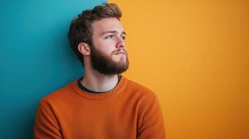 Portrait of a stylish young man with a beard wearing a mustard sweater, set against a vibrant gradient background. photo