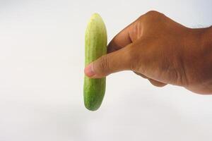 Hand Displaying Fresh Cucumber Against a White Background photo