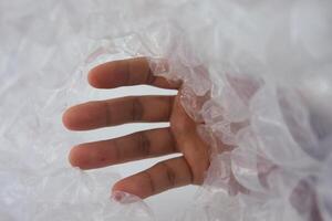 Hand Reaching Through Transparent Bubble Wrap, Symbolizing Exploration and Curiosity photo