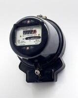 A close up of a vintage Soviet era single phase electric meter mounted on a white wall. The black housing and retro design emphasize its historical value and engineering significance photo