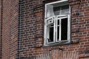 A fragment of a brick wall and a broken window of an old abandoned house. photo