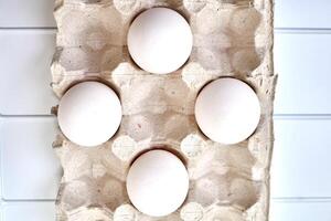 White eggs in a packing carton on a plastic surface photo