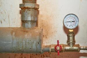 Pressure sensor, meter and faucet on the water pipe in the basement photo