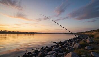 Fishing rod extends over serene water at sunset with rocky shoreline view photo