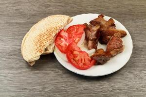 Greek souvlaki with pita bread and vegetables close-up on the table. Pork pita table photo
