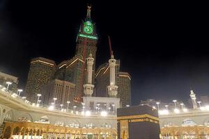 Makkah, Saudi Arabia, 2024 - View of the crowd of Muslims around the Kaaba at night with the Clock Tower in the background photo
