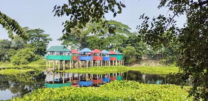 Houses on stilts by the lake, colorful houses on stilts in the middle of a lake, a small house sitting on stilts in the middle of a lake, photo