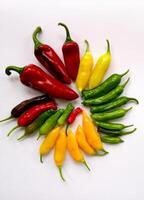 RED, YELLOW, PURPLE AND GREEN FRESH CHILLIES ON A WHITE BACKGROUND photo