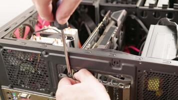 caucasian hands screwing in graphics card in pc case during installation or upgrade video
