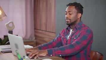 sério africano americano homem trabalhos em computador portátil digitando enviando mensagem para cliente. video