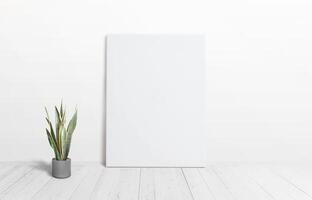 Vertical art canvas against the wall with a plant on the floor and wooden white floor. Clean surface ideal for mockup art presentation photo