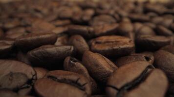 A close up view of roasted coffee beans. The beans are dark brown and have a smooth, shiny texture. Coffee industry concept. Moving camera. video