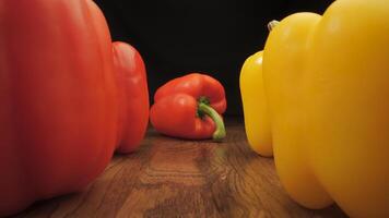 Red and yellow peppers on a wooden surface. The camera moves between the vegetables. Cooking concept. video