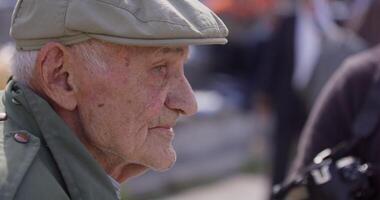 A close-up view captures an elderly man engaged in conversation, enjoying a cigar, and sporting a vintage hat, exuding a sense of wisdom and character video