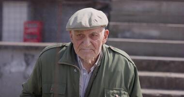 A close-up view captures an elderly man engaged in conversation, enjoying a cigar, and sporting a vintage hat, exuding a sense of wisdom and character video
