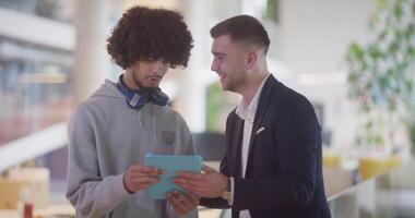 In a modern office setting, an African American businessman engages in a discussion with his director, using a tablet to address business challenges, symbolizing collaboration and technology video