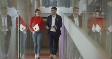 In the dynamic environment of a modern startup company, the director engages in a discussion with his young business colleague while they walk, reflecting the spirit of collaboration and innovation in video