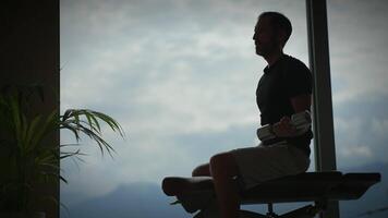 The silhouette of a man engaged in exercise with weights set against a beautiful scenic background video