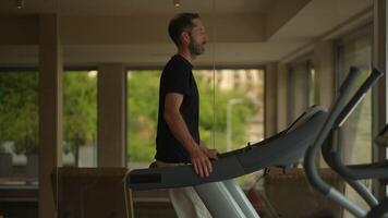 A man is seen exercising on a treadmill within a stateoftheart gym environment video