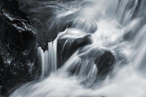 A man is standing on a rock in front of a waterfall photo