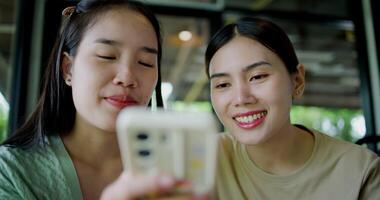 Handheld selective focus shot, Two siblings are playing social media together on smartphone while sitting at a table in a cafe. Family enjoying happy time together. video