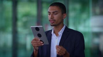 A professional man is actively using a tablet in a contemporary office environment setting video
