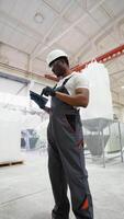 Worker of pvc windows factory a tablet on production line. Vertical video