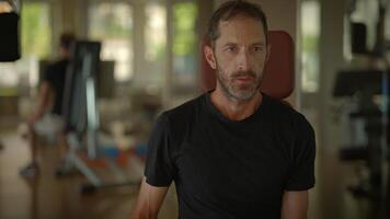 A man is performing an exercise routine using a dumbbell in the gym to enhance fitness levels video