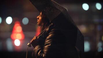 A woman with an umbrella walks through a rainy city night, dressed warmly and elegantly video