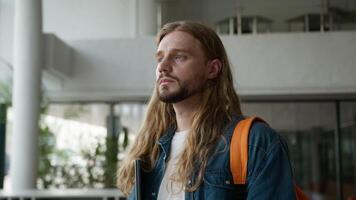 Dreaming pensive serious calm thoughtful man male guy student think looking away pondering look at camera holding laptop portrait in university college education studying learning learn study course video