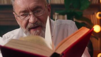 Old Caucasian man grandfather reading book novel history home library literature educated well-read pensioner aged antique business exploring information intelligence cognition page paper learn text video