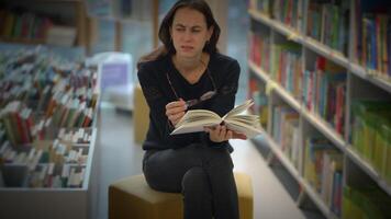 A thoughtful reader in a library, surrounded by books, deeply engaged in their reading video