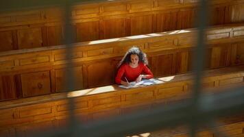 Distant view Caucasian girl student Hispanic woman Latina American female in university college auditorium high school academy writing task homework test exam write in classroom study education learn video