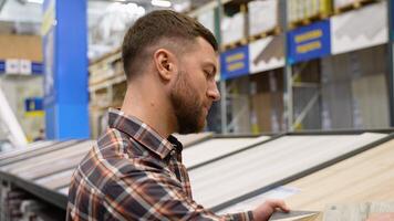 A man looks at different types and colors of floor coloring in a store video