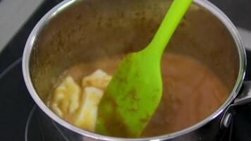 Melt butter and cook caramel. stirring a caramel paste in a pan in the process of creating delicious caramel sweets. video