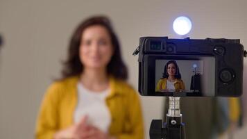 Modern cheerful Caucasian woman blogger girl influencer talking filming vlog using web camera device on stabilizer. Streamer female vlogger shooting review blog smile explain lifehacks in studio video