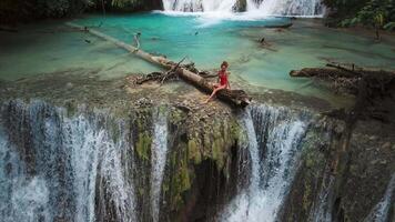 Woman relaxing on cascade waterfalls with blue water in Central Sulawesi, drone view. Scenic waterfall in Luwuk video
