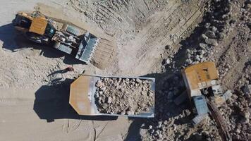 Quarry mining, work of the excavator and dump trucks, aerial view video
