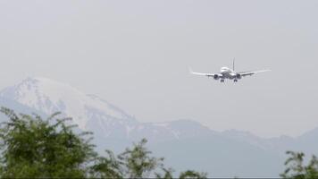 Plane landing at Almaty airport. Flight arriving. Airplane flying against the backdrop of mountains. Travel concept video