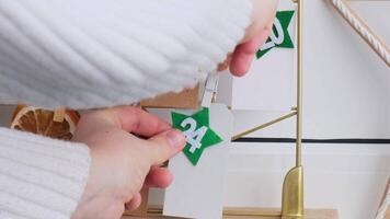 Number on craft paper notes with tasks before Christmas holidays. Female making kraft paper for handmade advent calendar Made with your own hands step by step DIY crafts do it yourself video