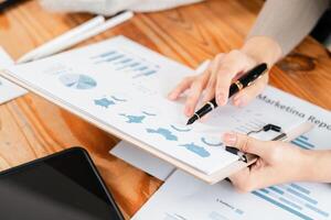 Close-up of hands reviewing marketing report with charts and graphs on a clipboard, highlighting business analysis. photo