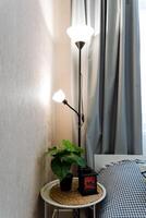 An elegantly designed lamp stands gracefully on a charming table that is situated next to a cozy bed, effectively creating a warm and inviting atmosphere that fills the entire room photo