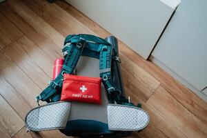 A sturdy backpack is placed on a polished wooden floor right next to an essential first aid kit, ready for any emergency situations that might arise while traveling or hiking photo
