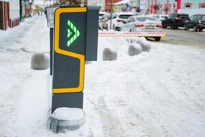 In a winter landscape, there stands a parking meter covered in snow with a bright green light glowing on it, indicating that parking is available despite the freezing cold weather photo