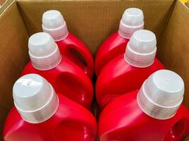 Inside a sturdy and wellconstructed box, there are four vibrant red bottles with shiny white caps, securely stored and meticulously prepared for transport to carry various types of liquids photo
