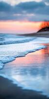 A beautiful sunset over the ocean with a tree in the background. The water is calm and the sky is a mix of orange and pink hues photo